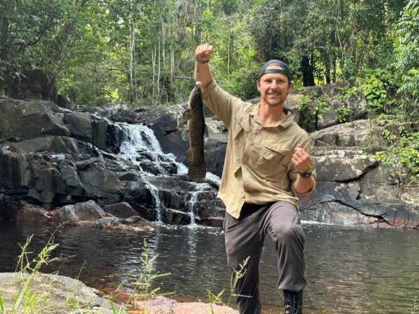 Guest on mountain expedition catching a fish in the jungle mountains